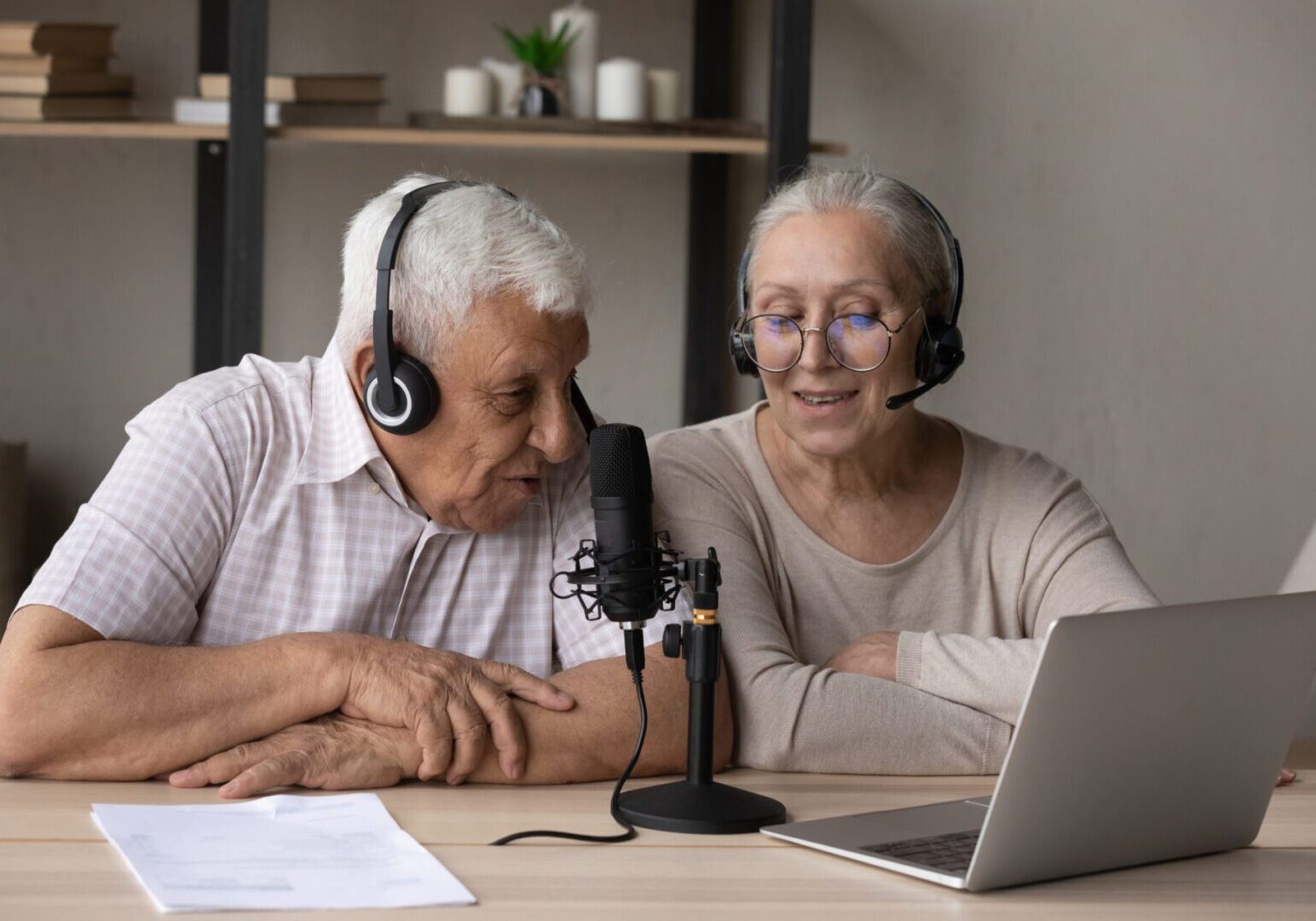 Elderly couple recording a podcast together at home.