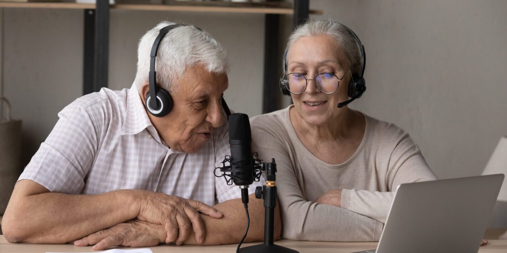 Elderly couple recording a podcast together at home.